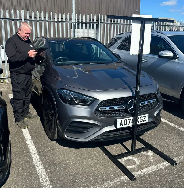 AWG Windscreens technician performing ADAS camera calibration with target board on a Mercedes
